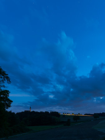 The village Eichlberg near Hemau with church of pilgrimage and surrounding rural area on top of a hill in Bavaria at night with stars and milky wayの写真素材