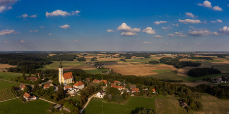 Aerial drone panorama of the village Eichlberg near Hemau with church of pilgrimage and surrounding rural area on top of a hill in Bavaria in sunlightの写真素材