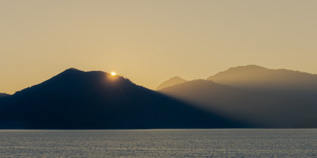 Idyllic calm soothing morning scenery at mountain lake Walchensee in Bavaria, Germany at dawn with sun rising behind mountainの写真素材