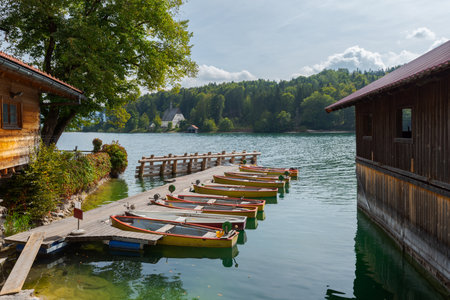 Rental row boats on pier at mountain lake Walchensee in Bavaria, Germany on sunny day with boat houseの写真素材