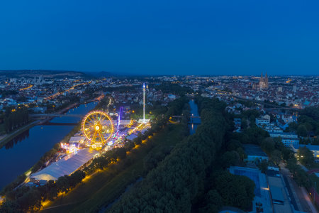 Aerial drone view of the fair Maidult in Regensburg, Bavaria, Germany with ferris wheel and beer tents at nightの写真素材
