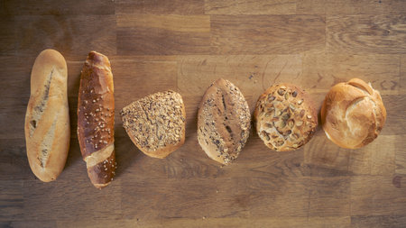Flat lay of selection of a variety of different buns, rolls and sticks from bakery aligned side by...
