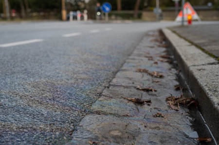 Shimmery and shiny trail and puddle of oil, gasoline or diesel on the side of paved roadの写真素材