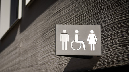 Sign for public restrooms, toilets, with male, female and handicapped, disabled people pictogram symbol on modern gray house facadeの写真素材