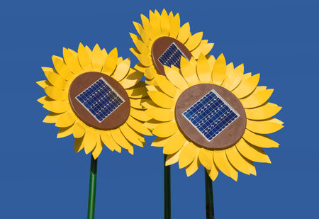 Three huge sunflower dummies with solar cells standing against a cloudless blue skyの写真素材