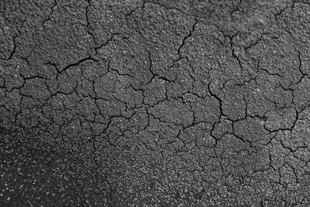 Surface of a black, sanded, cracked bitumen roofing felt