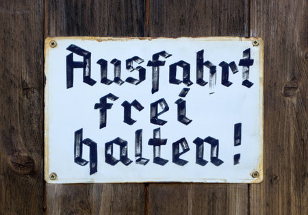 Hold exit free - - Old, hand-painted sign in old German lettering Keep exit free - on a brown wooden garage door.の写真素材