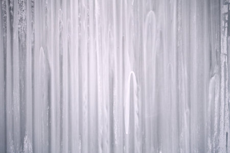 Blurred structure of a run down paint on a glass surface in white and gray with fine dark spotsの写真素材