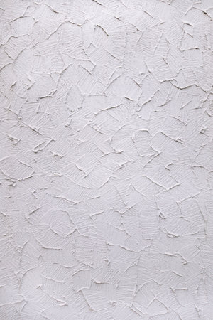 Detail shot of white-gray plaster with abstract pattern on exterior wall to