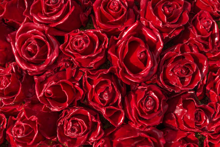 Red roses made of wax - close up of a decoration of artfully produced and tightly juxtaposed artificial rose bloomsの写真素材