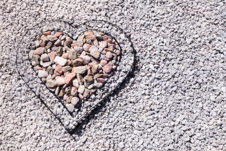 Heart of black metal wire filled with small stones, created as a decoration in the garden of a modern villa.の写真素材