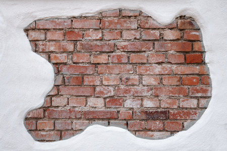 Old, strongly dirty, red brick wall, that was partially covered with white plaster, taken in close-up.の写真素材