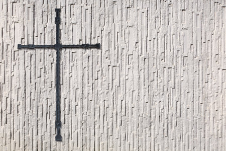 Anthracite cross made of metal on a white wall with very coarse textureの写真素材