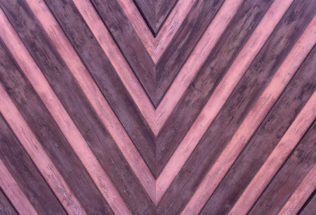 Detail of an old weathered wooden wall with pointed striped pattern in pink and purpleの写真素材