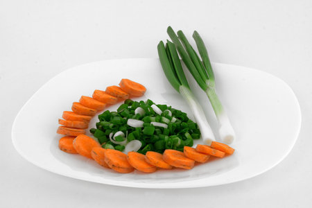 Serrate stone leek and carrot on white plateの写真素材