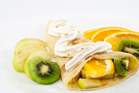 Pancakes with kiwi, orange, apple and creme isolated on white backgroundの写真素材