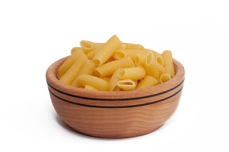 Raw macaroni in wooden bowl isolated on whiteの写真素材