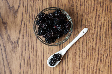 Glass bowl of blackberries with ceramic spoonの写真素材