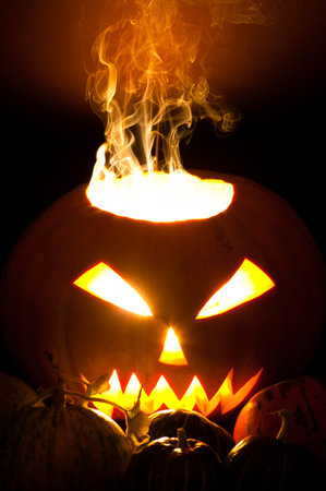 Smoky Halloween pumpkin Jack-o-lantern and small pumpkins in foregroundの写真素材