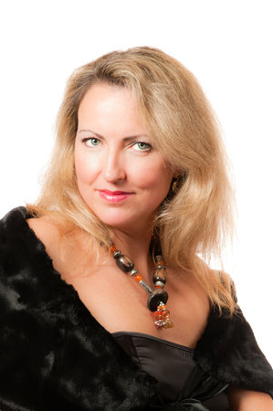 Beautiful attractive blond caucasian wealthy woman with big necklace around her neck and fur on her shoulders directly smiling in cameraの写真素材