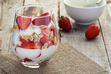 Yogurt with muesli and strawberries in glass isolated on white backgroundの写真素材