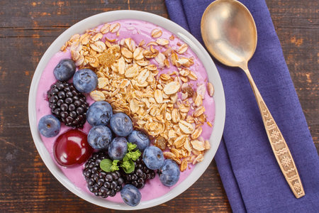Dish of yogurt smoothie , blackberries, blueberries, cherry and muesli on wooden table. Rustic style. Top view.の写真素材