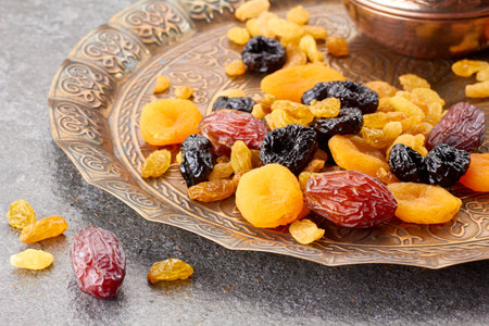 Various dried fruits on toreutic plate over stone backgroundの写真素材