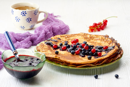Thin pancakes stack with blueberries and red currant jamの写真素材