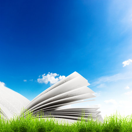 Open book in green grass over blue sky. Magic bookの写真素材