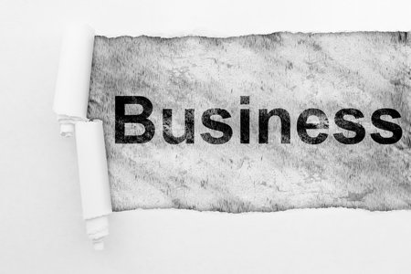 Closeup of a hole in paper over word business on grunge background. Business conceptの写真素材