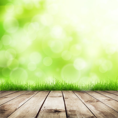 Fresh spring green grass with green bokeh and sunlight and wood floor  Natural backgroundの写真素材
