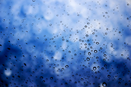 Water drops on glass with blue bokeh backgroundの写真素材