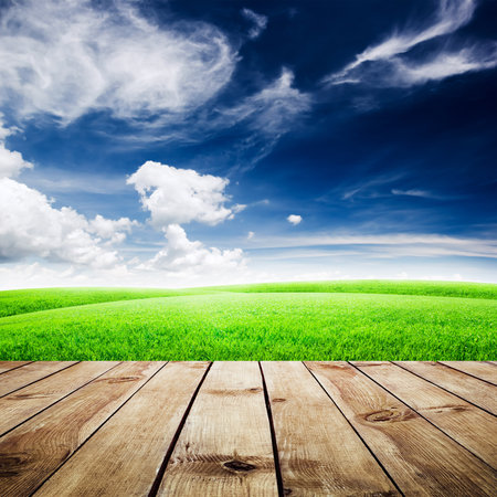 Green field under blue sky. Wood planks floor. Beauty nature backgroundの写真素材