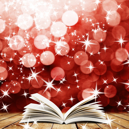 Old open book with magic light and falling stars on wood planks and dark abstract backgroundの写真素材