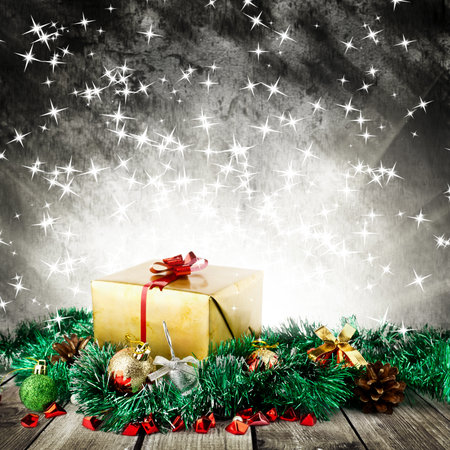 Golden christmas gift box with christmas balls on wood planks over dark background with lightの写真素材