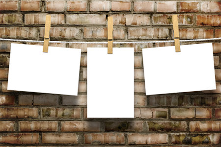 Photo frames with pins on rope over old aged brick wall background