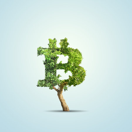 Green tree shaped in bitcoin sign isolated on blue backgroundの写真素材