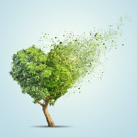 Green tree shaped in heart disintegrate over blue backgroundの写真素材