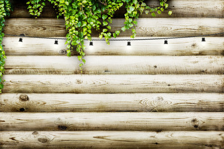 Garland lamps over wooden board fence with green leaves. Decoration backgroundの写真素材