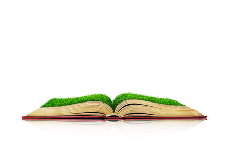 Open book with green grass field on it isolated over white background. Concept imageの写真素材