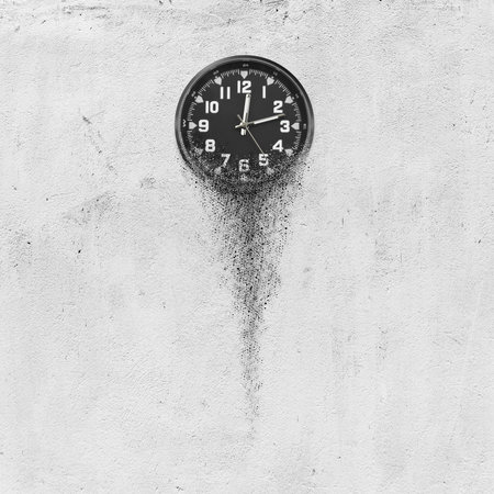 Classic clock on white concrete background disintegrate in a small parts and flowing away. Time flying conceptの写真素材