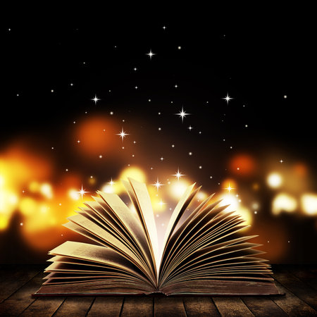 Open book on wooden vintage table with mystic magic bright light on backgroundの写真素材