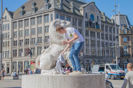 Tourist On A Lion Belonging To The Remembrance Of The Dead Statue At Amsterdam The Netherlands 2018のeditorial素材