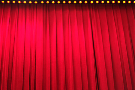 deep bright red closed curtain under stage lightの写真素材