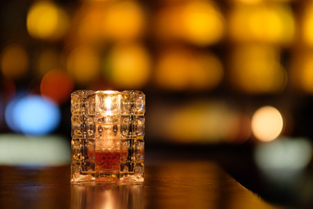 close up a candle light in glass on table in bar. Colorful bokeh at nightの写真素材