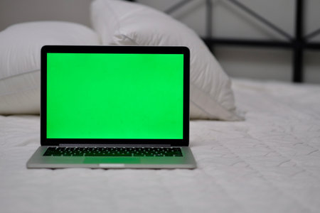 one green screen laptop computer on bed.