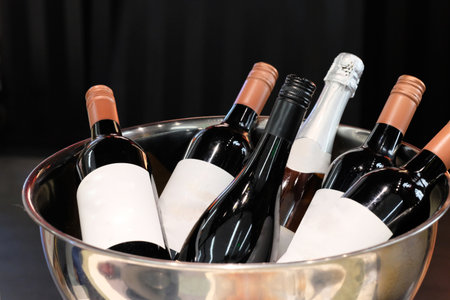 close up several bottles of wine with blank label in silver shiny basin. black backgroundの写真素材