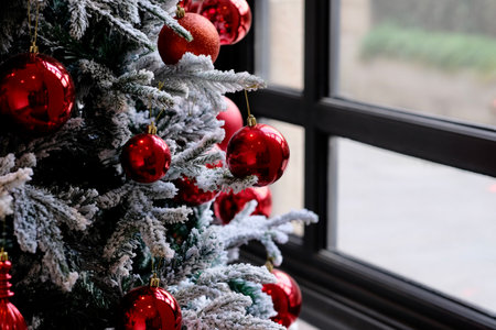close up red balls decoration on christmas tree close to window