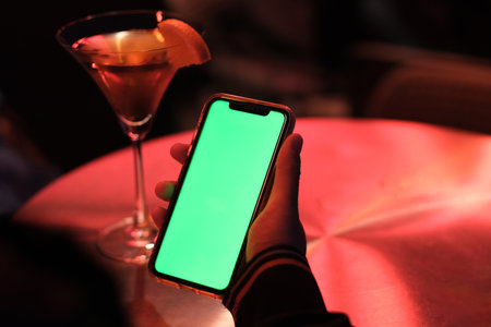 over shoulder view of people holding green screen smart phone at night club.の写真素材