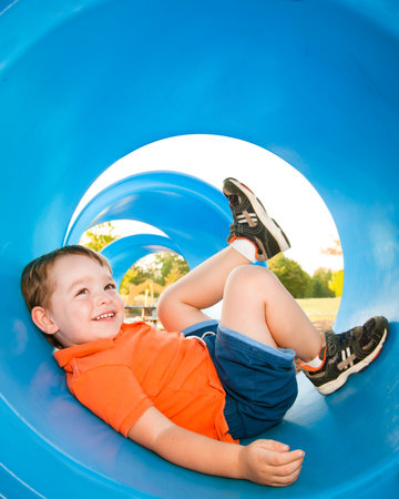 Cute young boy playing in tunnel on playground. の写真素材